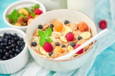 Sağlıklı vejetaryen kahvaltı. Yulaf ezmesi, granola ahududu ve yaban mersini kase üzerinde mavi arka plan, buket lavanta ile. Üstten görünüm. Düz yatıyordu. 