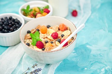 Sağlıklı vejetaryen kahvaltı. Yulaf ezmesi, granola ahududu ve yaban mersini kase üzerinde mavi arka plan, buket lavanta ile. Üstten görünüm. Düz yatıyordu. 