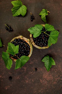Blackcurrant meyveler yaprakları, siyah frenk üzümü yeşil kase ile. Üstten görünüm. Uzay kopyalayın. Düz yatıyordu. Yaz veya bahar kavramı. Hasat.