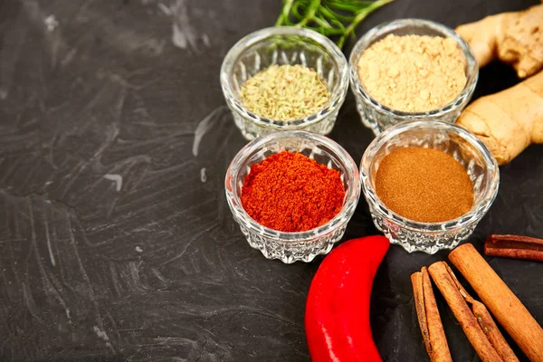 Fresh and dried seasoning herbs and spices -  paprika, ginger, cinnamon, rosemary in bowls. Colourful various herbs and spices for cooking on black background. Top view. Copy space. Flat lay.