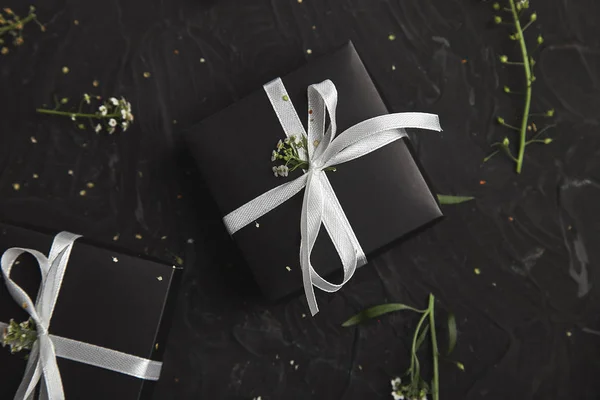 春天的概念 包装现代圣诞节或生日礼物 黑色和白色的礼品盒与鲜花 平坦的平面 顶部的景色 — 图库照片