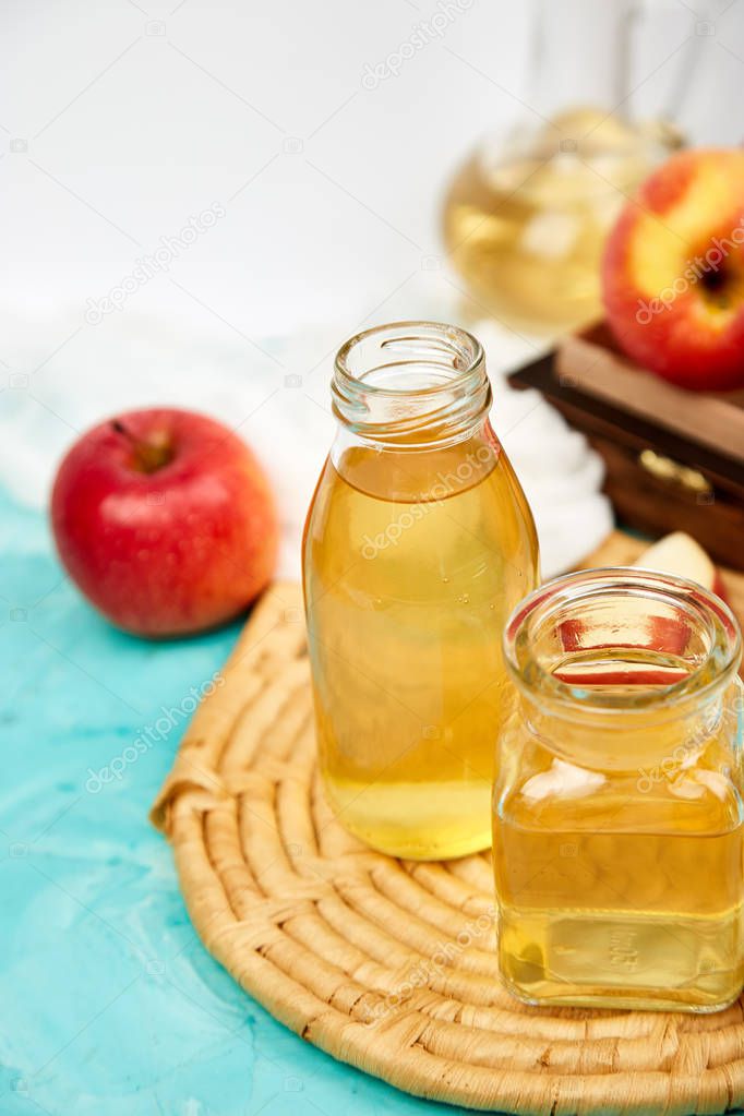 Glass Bottle of apple organic vinegar on blue background. Apple cider vinegar.