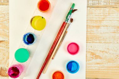 Suluboya paletleri ve boya fırçaları. Sanatçı ahşap arka plan üzerinde çalışma alanı. Çok az. Yaratıcı. Düz yatıyordu. Üstten görünüm. Kopya alanı. 