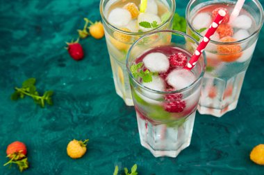 Aromalı su üç rengiyle ahududu - infused detoks kırmızı, turuncu, yeşil zemin üzerine sarı. Yaz ev yapımı kokteyl serinletici