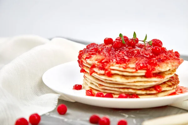 American pancake with jam - berry, viburnum, cranberry on grey background. Homemade pancakes with berry sauce and mint. Healthy breakfast with fresh hot pancakes with berry jam