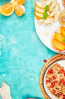 Kolay kahvaltı kavramı. Smoothies granola ve tropikal meyve - nar, mandalina, Trabzon hurması, apple ile pirinç gevrek ekmek kase. Yaz vegan, beslenme, organik doğal gıda. Üstten görünüm. Kopya alanı. 