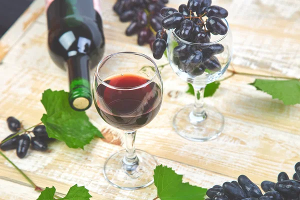 Red wine concept with bottle, glass and grapes on wooden background. Wine header image. Wineglasses