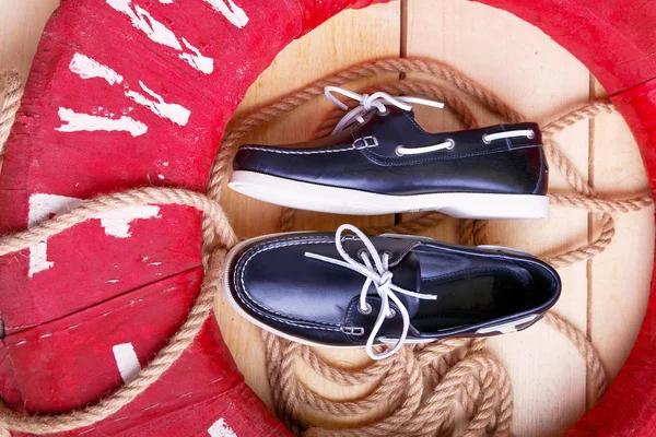 Stock image Blue boat shoes on wooden background near red lifebuoy and rope. Top view. 