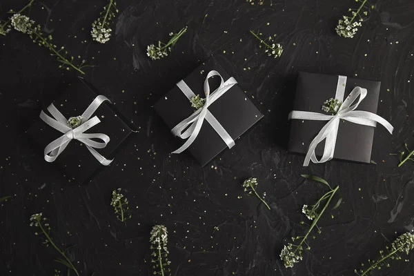 Wrapping modern Christmas or Birthday gifts presents. Gift boxes in Black and White color with flowers. Flat lay, top view. Beautiful.