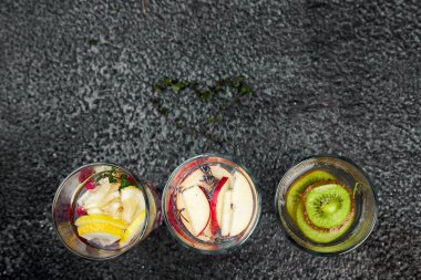 Detoks çeşitli infüzyon su kivi, elma, lavanta, zencefil, limon, siyah arka plan üzerine nane. Yaz ev yapımı kokteyl serinletici. Diyet. Sağlıklı içecek. Üstten Görünüm. Kopya girintili
