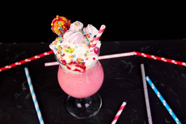 Berry, rasberry, çilek, çikolata şekerleme, lolipop siyah arka plan üzerine pembe aşırı milkshake... Deli freakshake. Uzay kopyalayın. Gıda trend Overshake