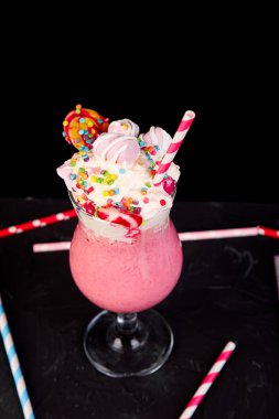 Berry, rasberry, çilek, çikolata şekerleme, lolipop siyah arka plan üzerine pembe aşırı milkshake... Deli freakshake. Uzay kopyalayın. Gıda trend Overshake