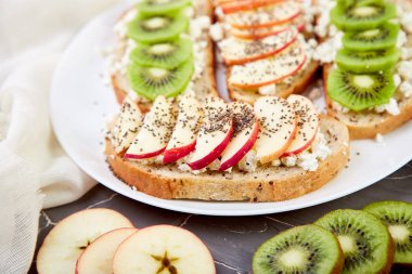 Sağlıklı kahvaltı tost kivi, elma, peynir ve chia tohum beyaz plaka ve gri arka plan ile. Diyet yemekleri. Vejetaryen. Yakın çekim.