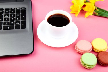 Kadın ya da laptop, defter, fincan kahve, macarons ve çiçekler nergis pembe tablo ile kadınsı çalışma alanı
