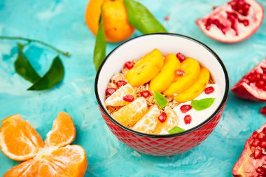 Tropikal smoothies meyve kahvaltı ev yapımı granola yoğurt nar, mandalina, Trabzon hurması mavi arka plan üzerinde top. sağlıklı organik katmanlı tatlı. Diyet, vegan gıda. Üstten görünüm