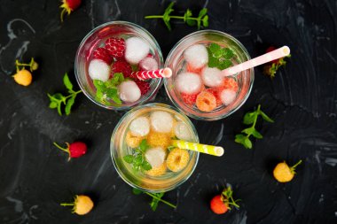 Aromalı su üç rengiyle ahududu - infused detoks kırmızı, turuncu, siyah zemin üzerine sarı... Yaz ev yapımı kokteyl serinletici. Üstten görünüm