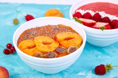 Güler yüzlü kase. Mavi arka plan üzerinde sağlıklı kahvaltı kase. Blackberry ve chia tohum ile kayısı güler yüzlü. Çilek ve Hindistan cevizi ile ahududu güler yüzlü. Vegan gıda