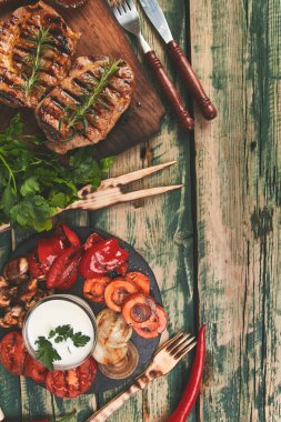 Izgara et. Rustik arka planda ızgara sebze çeşitli ahşap kesme tahtasında Steak domuz ızgara üst görünüm. Düz yatıyordu. Boşluk Kopyala.