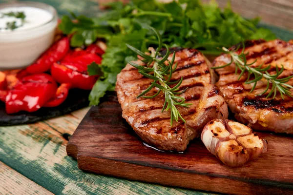 Grilovaný steak na dřevěné řezací desce s rozmankou grilované zeleniny. — Stock fotografie