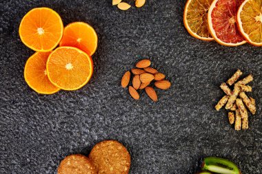 Sağlıklı aperatifler - çeşitli yulaf granola bar, pirinç cips, badem, kivi, portakal, siyah arka plan üzerine kurutulmuş. Mix ürün yelpazesine sahip. Üstten Görünüm. Diyet yemekleri. Gluten free Vegan