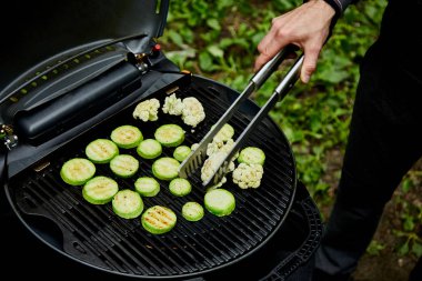 Büyük gaz ızgara üzerinde kabak sebze ızgara genç adamın eli . 