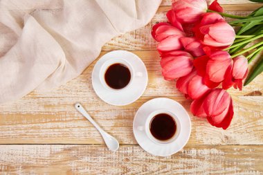Yukarıdan rustik ahşap masada pembe lale çiçek buketi ile kahve bardağı iki fincan, Günaydın. Kopyalama alanı. 