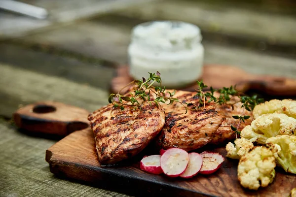 Grilled turkey meat. Steak turkey grill on wooden cutting board with a variety of grilled vegetables on  rustic background  Top view. Flat lay. Copy space