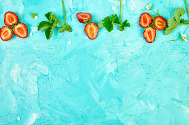 Mavi bir arka plan üzerinde çilek ile Düz yatıyordu kompozisyon. Çilek ve yapraklardan yapılmış renkli parlak desen. Meyve çerçevesi. Yaz konsepti. Düz yatıyordu, üstten bak. Kopyalama alanı.