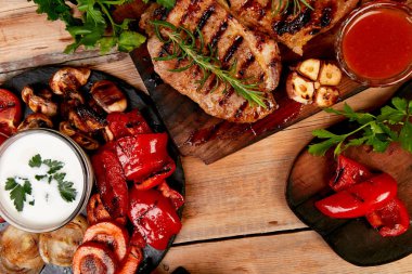Izgara et. Rustik arka planda ızgara sebze çeşitli ahşap kesme tahtasında Steak domuz ızgara üst görünüm. Düz yatıyordu. Boşluk Kopyala.