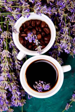 Kahve, fincan kahve taneleri ve yukarıdan yeşil arka plan üzerinde lavanta çiçeği. Günaydın konsepti. Kadın çalışma masası. Rahat kahvaltı. Mockup. Düz döşeme stili