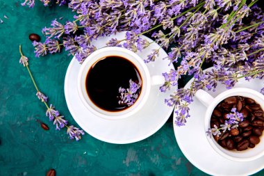 Kahve, fincan kahve taneleri ve yukarıdan yeşil arka plan üzerinde lavanta çiçeği. Günaydın konsepti. Kadın çalışma masası. Rahat kahvaltı. Mockup. Düz döşeme stili