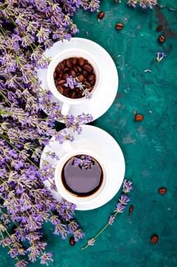Kahve, fincan kahve taneleri ve yukarıdan yeşil arka plan üzerinde lavanta çiçeği. Günaydın konsepti. Kadın çalışma masası. Rahat kahvaltı. Mockup. Düz döşeme stili