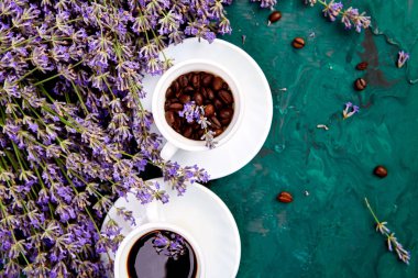 Kahve, fincan kahve taneleri ve yukarıdan yeşil arka plan üzerinde lavanta çiçeği. Günaydın konsepti. Kadın çalışma masası. Rahat kahvaltı. Mockup. Düz döşeme stili