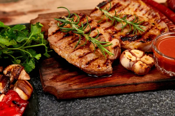 Grilovaný steak na dřevěné řezací desce s rozmankou grilované zeleniny. — Stock fotografie