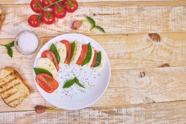 Dilimlenmiş domates, mozzarella peyniri, fesleğen, zeytin yağı ile İtalyan Caprese salatası. 