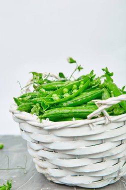Gri arka plan üzerinde taze yeşil bezelye ile Beyaz Sepet.