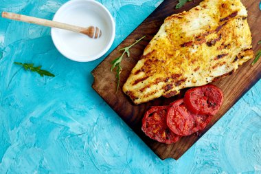 Mavi arka plan üzerinde ahşap tahta üzerinde domates ile ızgara pike fileto. Izgara deniz ürünleri. Barbekü balığı. Kopya alanı. Sağlıklı gıda.