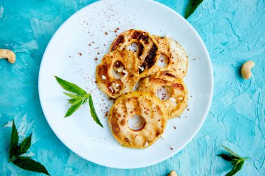 Mavi arka plan üzerinde beyaz plaka üzerinde cinamon ile ızgara elma.