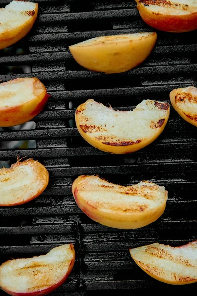 Grilled peach on black gas grill. Grilled dessert.