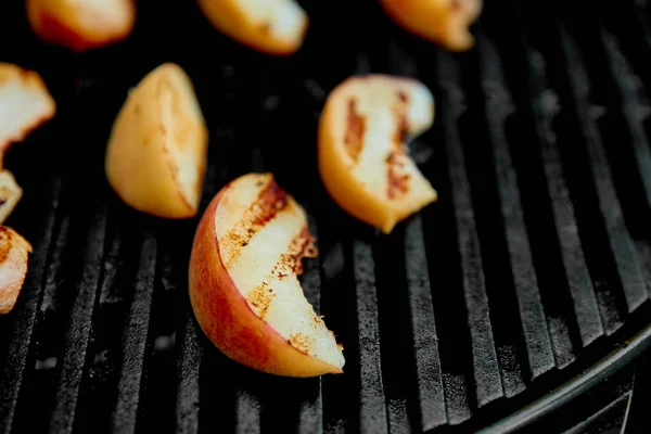 Grilled peach on black gas grill. Grilled dessert.