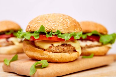 Işık arka planda ahşap masada zanaat sığır Burger. Sokak Yemeği, Fast Food. Peynir ve ahşap masada ev yapımı sulu hamburgerler. Boşluk Kopyala.