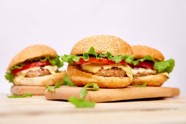 Işık arka planda ahşap masada zanaat sığır Burger. Sokak Yemeği, Fast Food. Peynir ve ahşap masada ev yapımı sulu hamburgerler. Boşluk Kopyala.