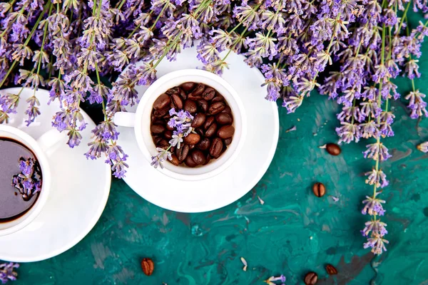 Coffee, coffee grain in cups and lavender flower on green background from above. Good Morning concept. Woman working desk. Cozy breakfast. Mockup. Flat lay style