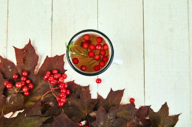 Beyaz ahşap arka plan, sonbahar akçaağaç kırmızı yaprakları ve beyaz arka plan üzerinde viburnum çilek ile Kupa veya sıcak viburnum çay fincan. Üst te. düz yatıyordu. kopya alanı. Kış. Noel. Soğuk mevsim.