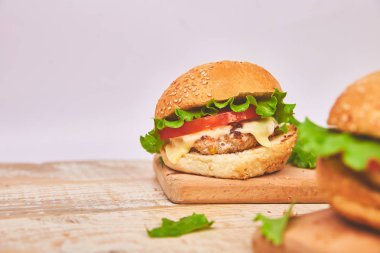 Işık arka planda ahşap masada zanaat sığır Burger. Sokak Yemeği, Fast Food. Peynir ve ahşap masada ev yapımı sulu hamburgerler. Boşluk Kopyala.