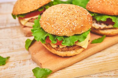 Işık arka planda ahşap masada zanaat sığır Burger. Sokak Yemeği, Fast Food. Peynir ve ahşap masada ev yapımı sulu hamburgerler. Boşluk Kopyala.