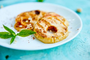 Mavi arka planda beyaz plaka üzerinde cinamon ile ızgara elma. Izgara tatlı. Barbekü meyvesi. Kopya alanı. Sağlıklı yiyecekler. Vegan gıda.