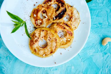 Mavi arka planda beyaz plaka üzerinde cinamon ile ızgara elma. Izgara tatlı. Barbekü meyvesi. Kopya alanı. Sağlıklı yiyecekler. Vegan gıda.