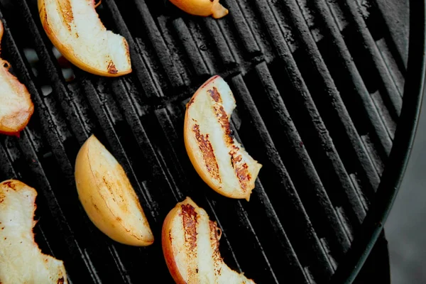 Grilled peach on black gas grill. Grilled dessert. Barbecue fruit. Copy space. Healthy food. Vegan food