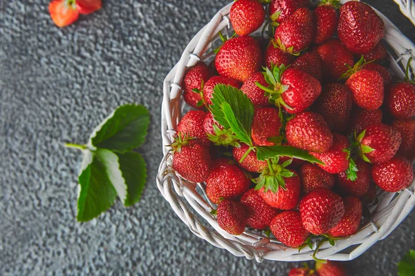 Ripe red strawberries on black background, Strawberries in white basket. Fresh strawberries. Beautiful strawberries. Diet food. Healthy, vegan. Top view. Flat lay.